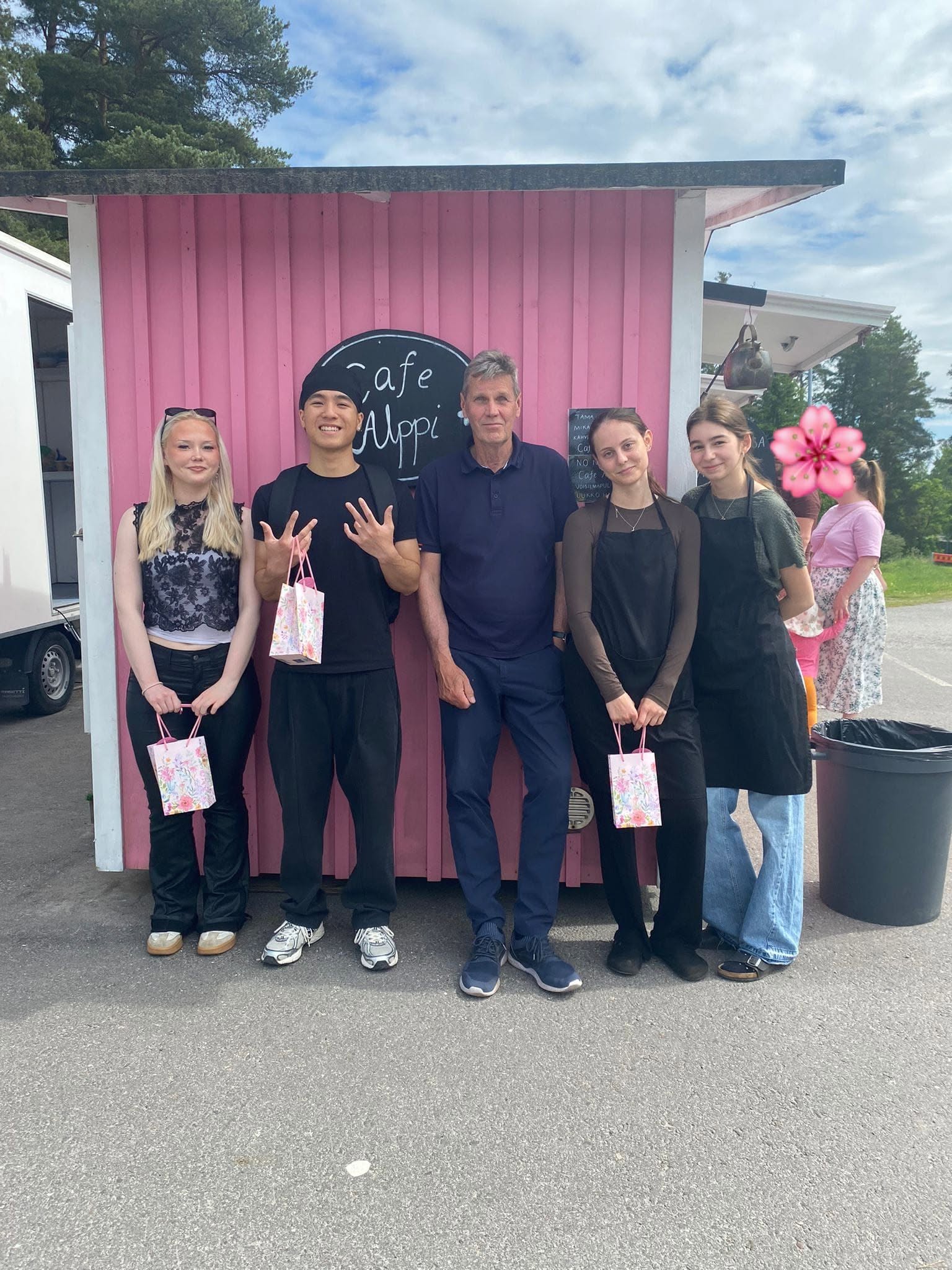 Viisi ihmistä seisoo rivissä Cafe Alpin pinkin kioskin edessä kesäpäivänä.